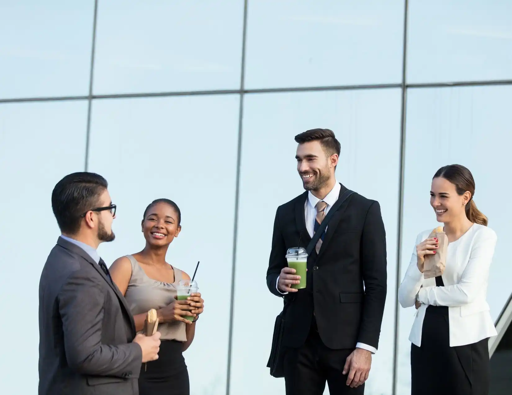 A group of business professionals enjoying drinks outdoors, engaged in conversation and networking in a relaxed atmosphere.