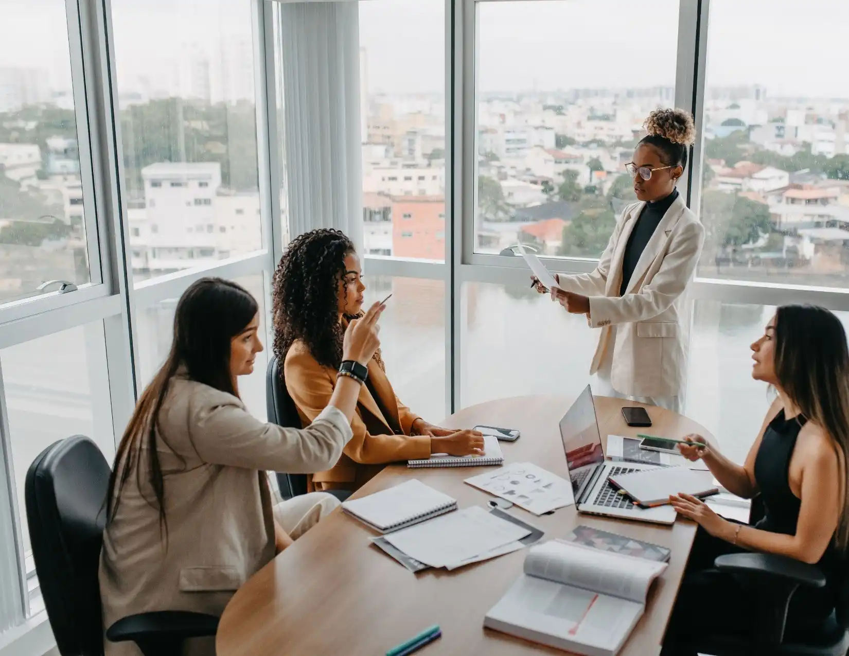 A group of professional businesswomen in an office setting, actively discussing strategies and ideas during a meeting.