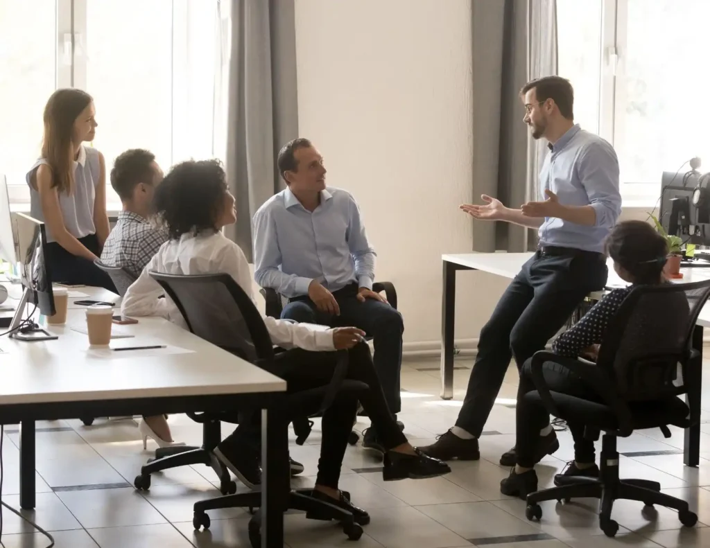 A team of people sitting in a circle at an office, actively participating in a meeting or brainstorming session.