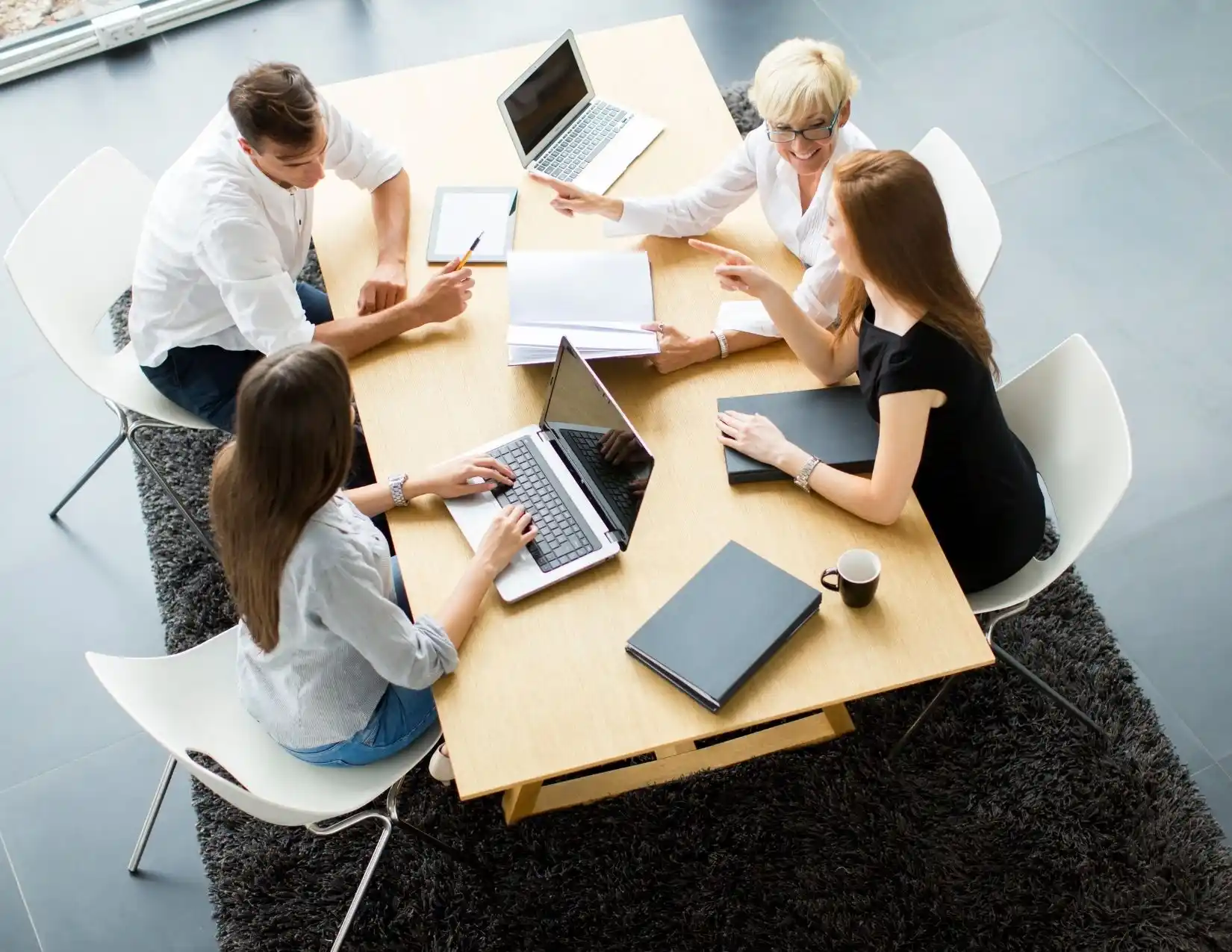 Aerial view of business professionals collaborating at a table, each using laptops for a productive meeting.