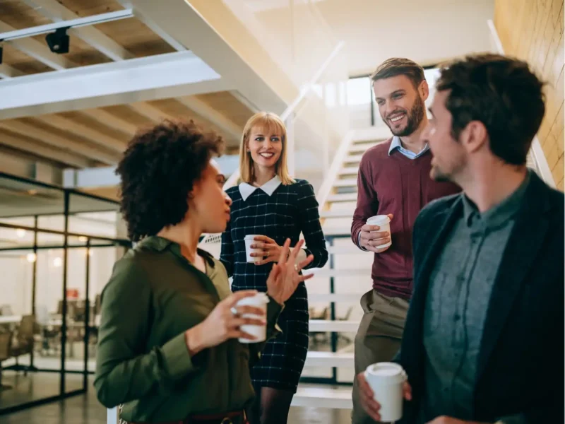 A group of business professionals enjoying coffee together in a modern office setting, fostering collaboration and conversation.