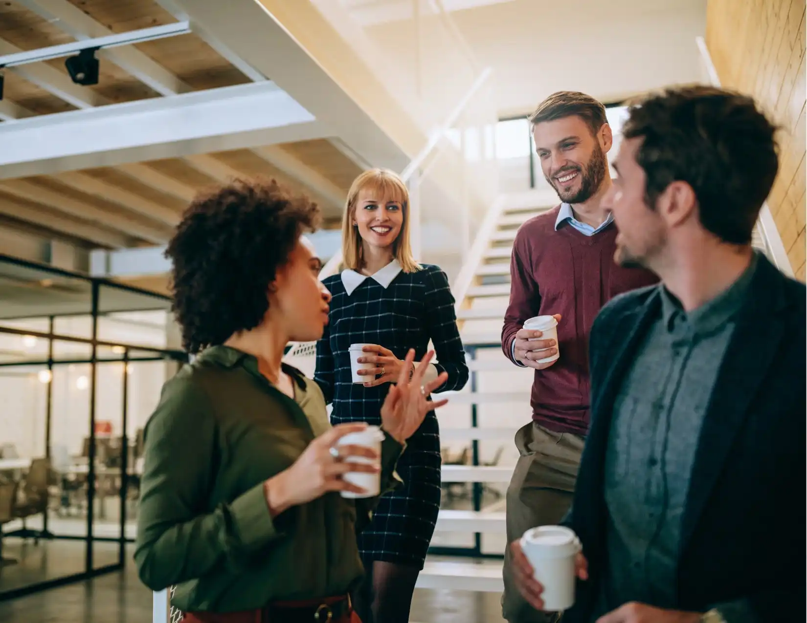 A group of business professionals enjoying coffee together in a modern office setting, fostering collaboration and conversation.