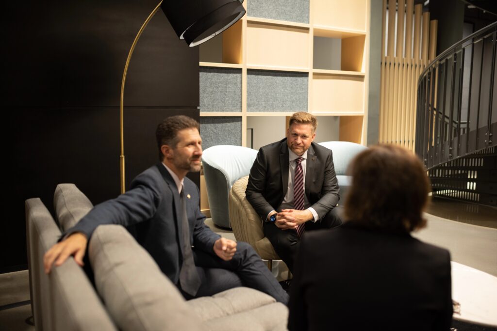 Three professionals engaged in a focused discussion on strategy and leadership in a modern lounge setting.