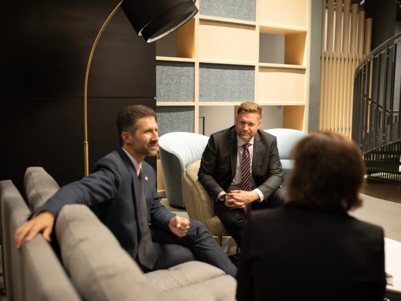 Three professionals engaged in a focused discussion on strategy and leadership in a modern lounge setting.